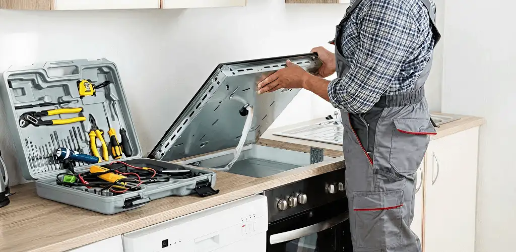 Handyman repairing a cooktop and checking wiring connections in Fargo, ND