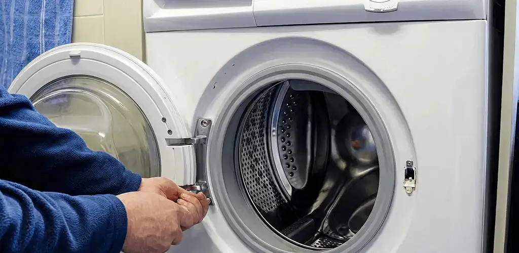 Washing machine repair handyman checking a front-load washer door and latch in Fargo, ND