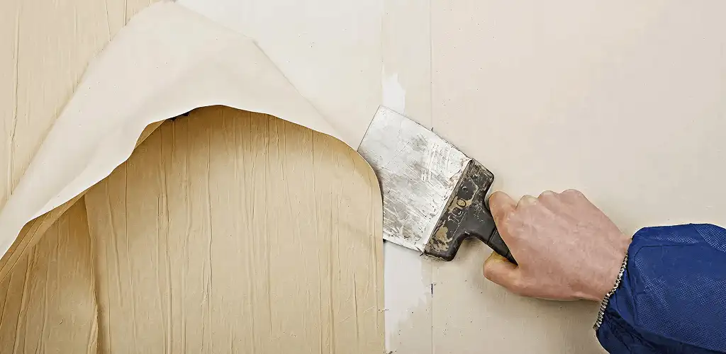 Handyman removing wallpaper with a scraper for wall preparation in Fargo, ND