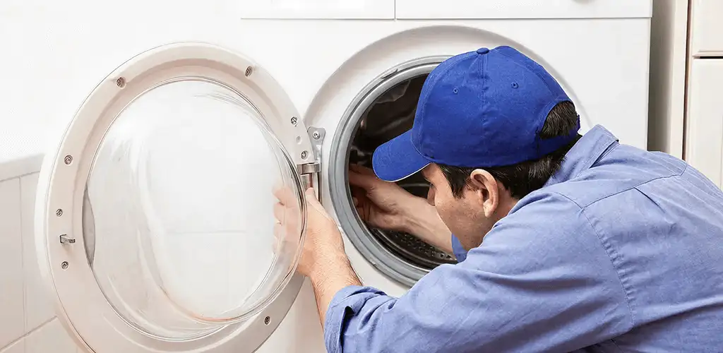 Washing machine repair handyman inspecting a front-load washer drum in Fargo, ND