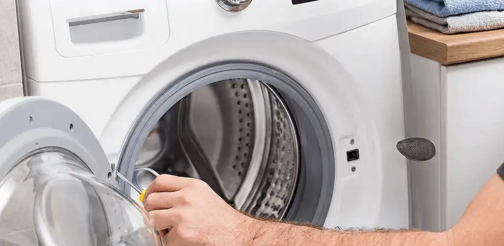 Handyman repairing a front-load washing machine and inspecting the drum in Fargo, ND